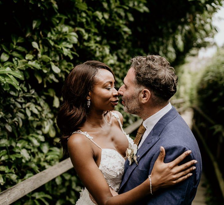 Black Bride in lace wedding dress with straps and Groom in navy suit embracing