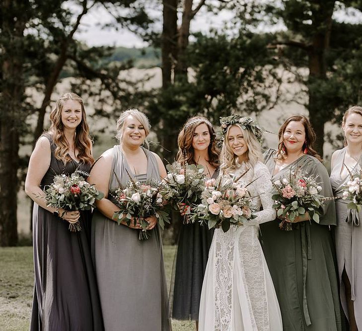 Bridesmaids in grey dresses clutch Protea bouquet