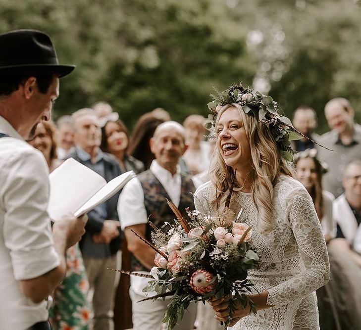 Bride laughs during ceremony holding a Protea bouquet