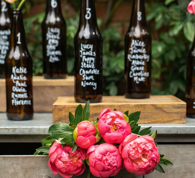 DIY table plan created out of dark brown beer bottles which have guests' names written upon them