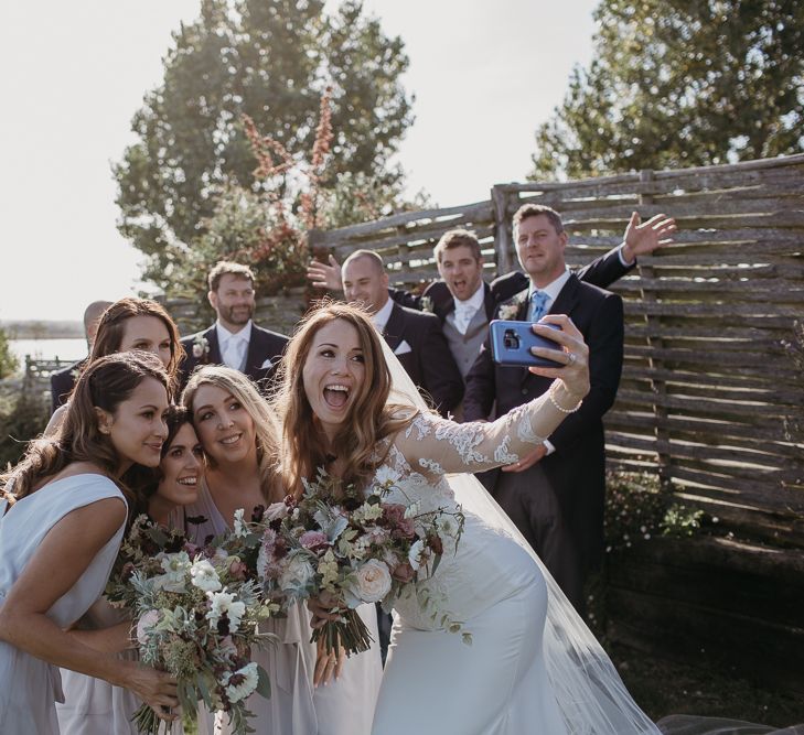 Bridal Party Taking a Selfie with the Groomsmen in the Background