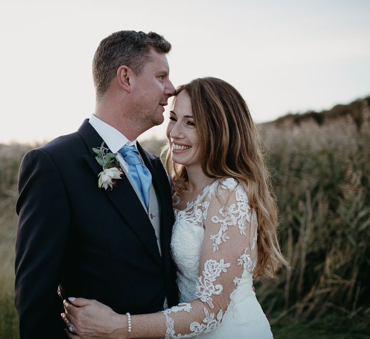 Bride in St Patrick Wedding Dress and Groom in Traditional Morning Suit Embracing.