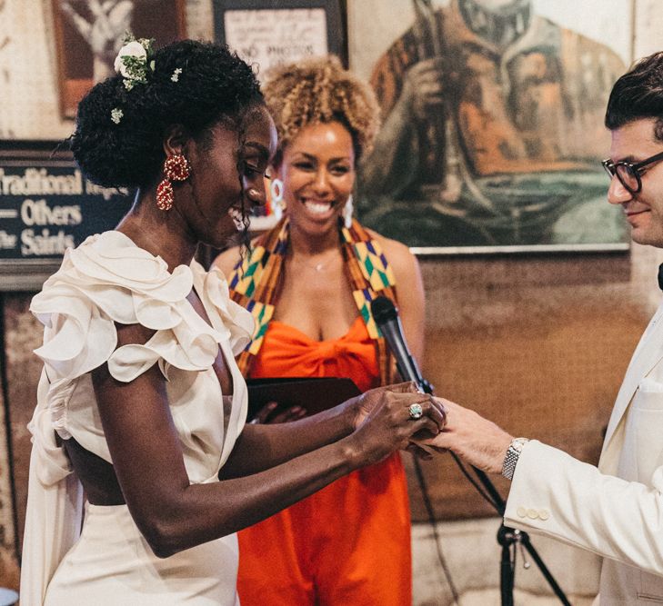 Stylish Bride and Groom in Ruffled Wedding Dress and White Tuxedo Jacket Exchanging Wedding Rings