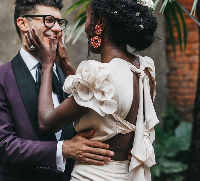 Bride in Johanna Ortiz Wedding Dress with Tie Up Back Detail and Ruffle Sleeves  Holding Her Grooms Face