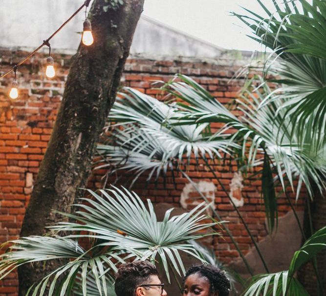 Black Bride in Johanna Ortiz Wedding Dress  with Ruffled Shoulder Detail and Groom in Burgundy Suit