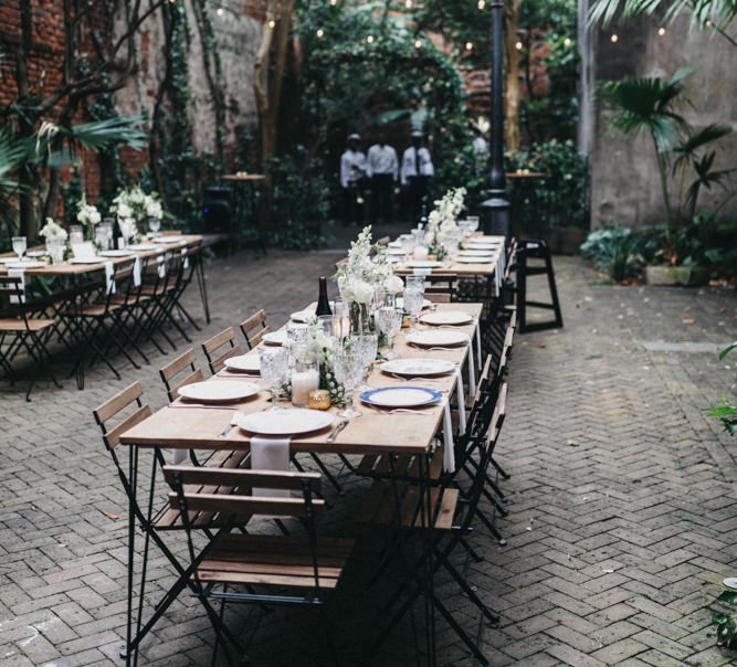 Outdoor Wedding Reception in a Courtyard with Plants and Festoon Light Wedding Decor