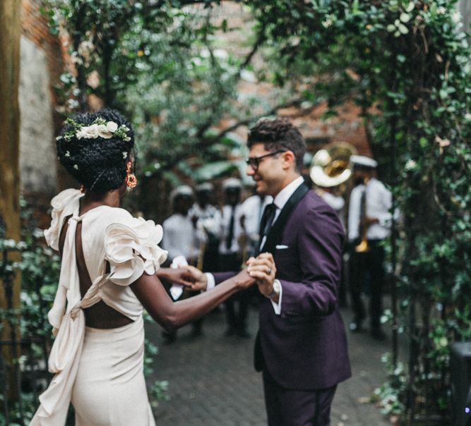 Stylish Bride in Ruffled Johanna Ortiz Wedding Dress and Groom in Burgundy Tuxedo Dancing