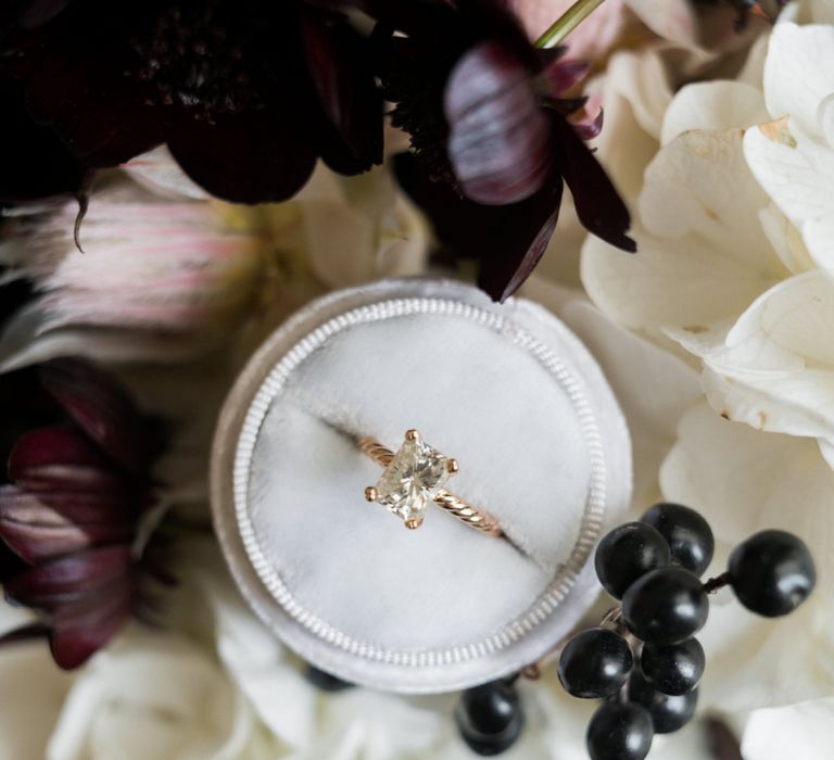 Diamond Engagement Ring in Ring Box Surrounded by Wedding Flowers