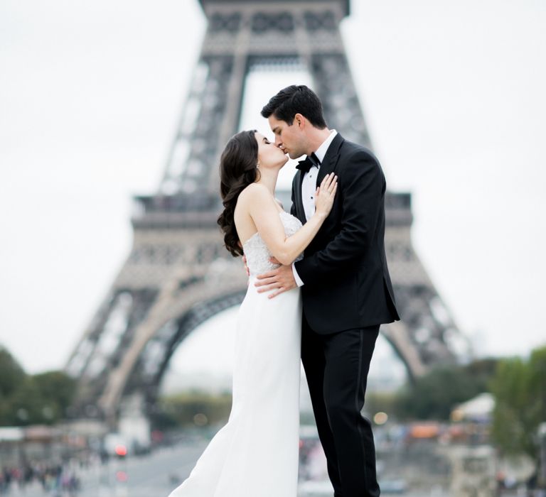 Bride in Tara Keely Wedding Dress and Groom in Black Tie Suit  Embracing in Front of the Eiffel Tower