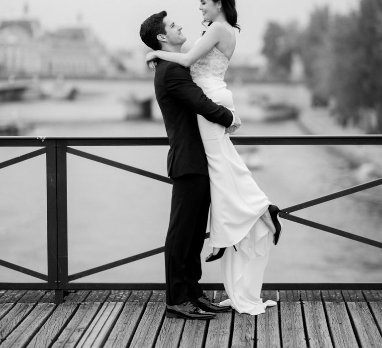 Groom Picking His Bride Up with the River Seine as Their Backdrop