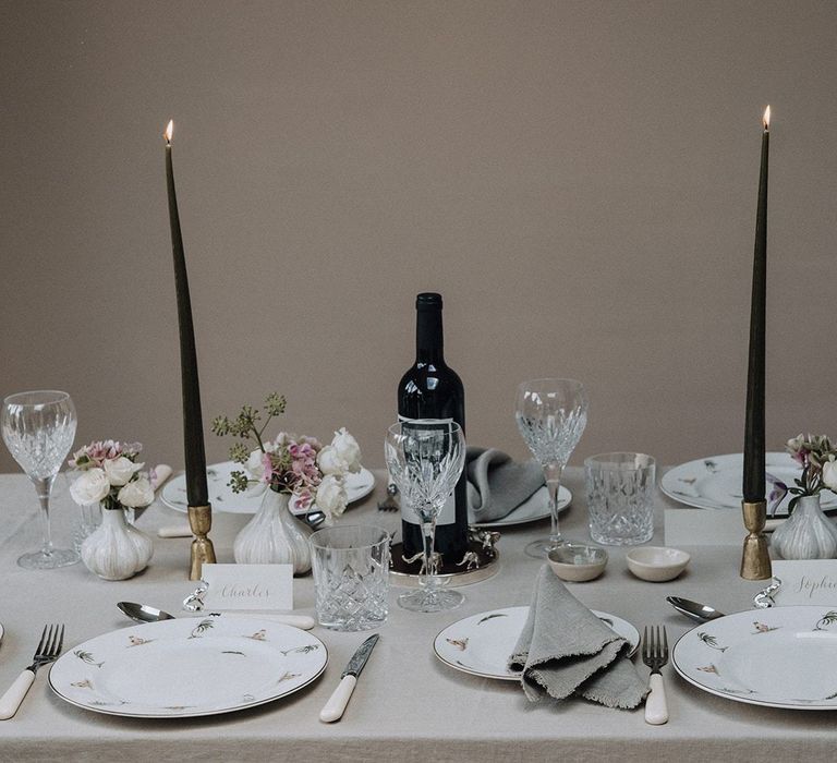 Intimate tablescape with neutral linens, black taper candles and blush flowers in bud vases