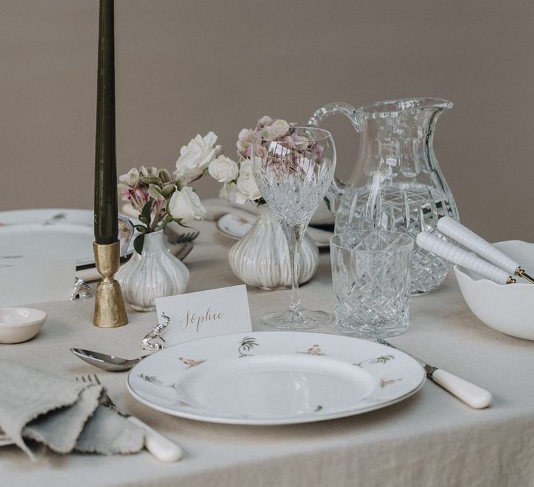 Place setting with patterned plate, taper candle and crystal glassware