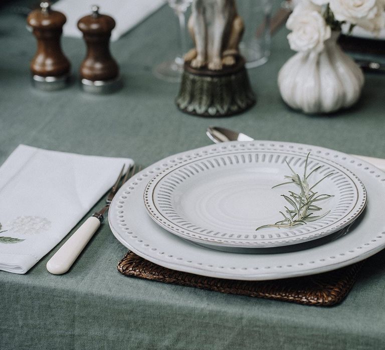 Place setting with leather mat, printed tableware and ivory cutlery