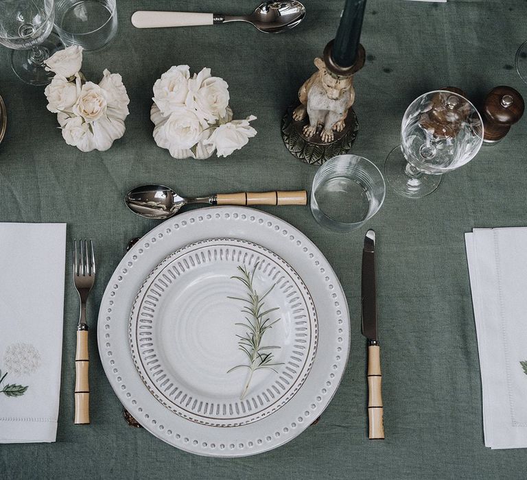 Place setting with patterned tableware, bamboo style cutlery and embroidered table napkins