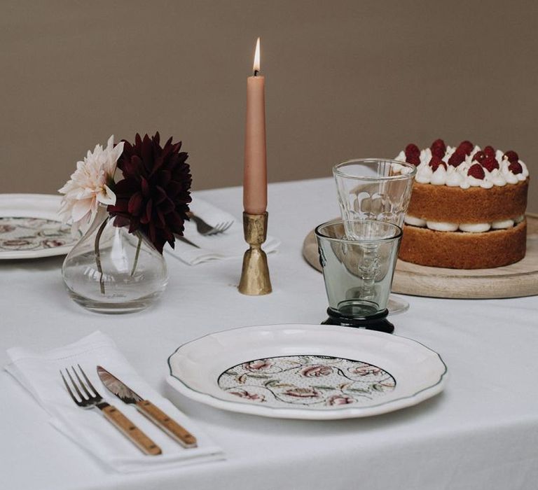 Place setting with patterned tableware, candles sticks and bud vases