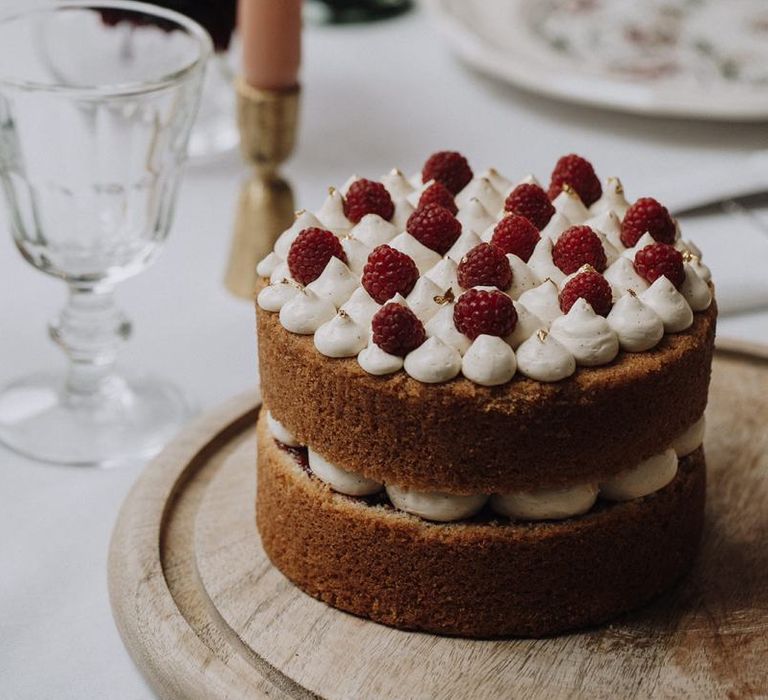 Naked cake with meringue kisses and raspberry topping