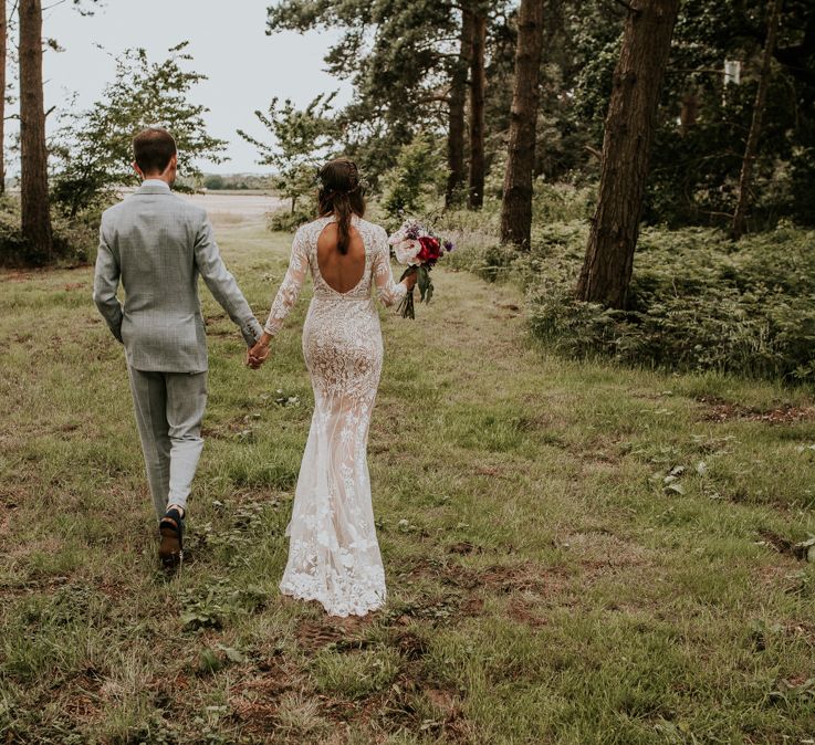 Open back lace bride dress with groom in grey suit