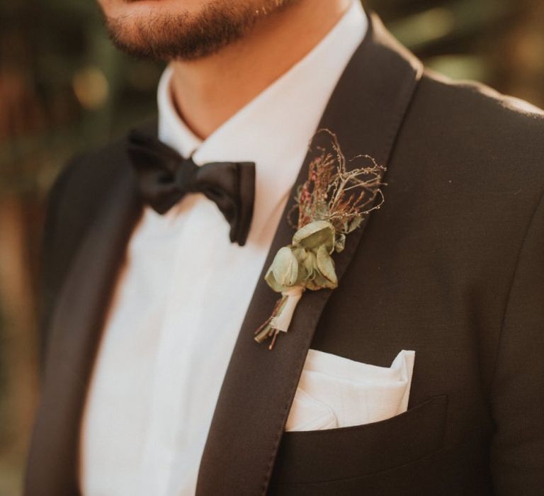 Groom in black tuxedo with bowtie and buttonhole