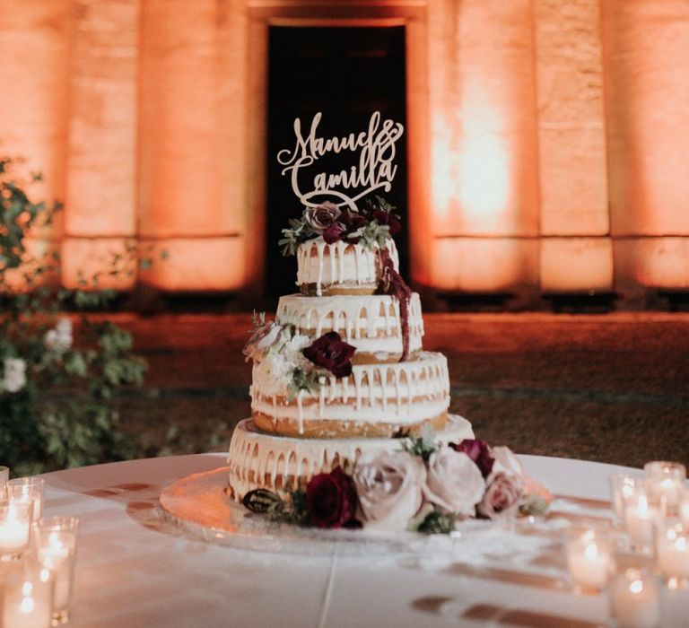 Drip wedding cake with personalised cake topper surrounded by candles