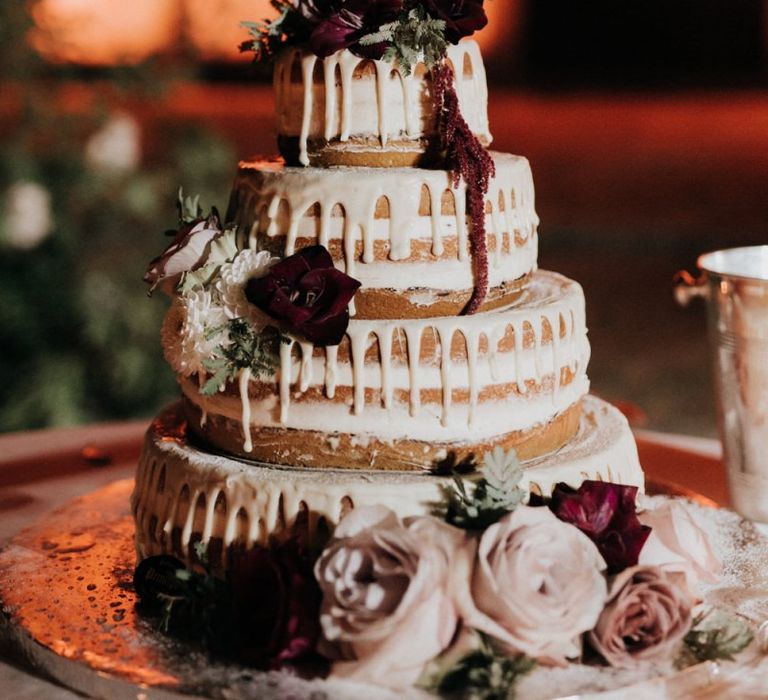 Candle lit drip wedding cake with flower decor