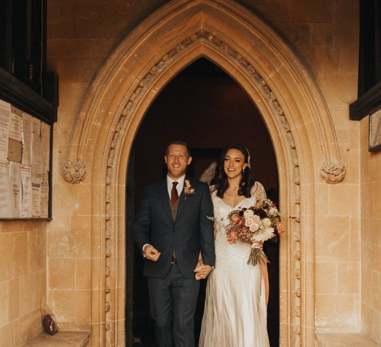 Bride in Maggie Sottero wedding dress and groom exit church ceremony