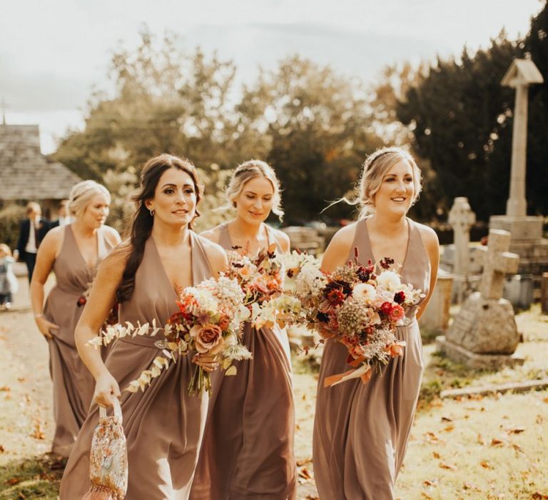 Bridesmaids in neutral dresses making their way to the church ceremony