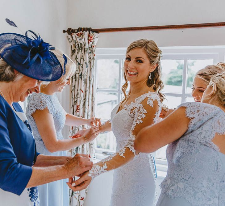 Mother of The Bride and Bridesmaids in Blue Dresses Helping the Bride into Her Lace Wedding Dress on the Wedding Morning