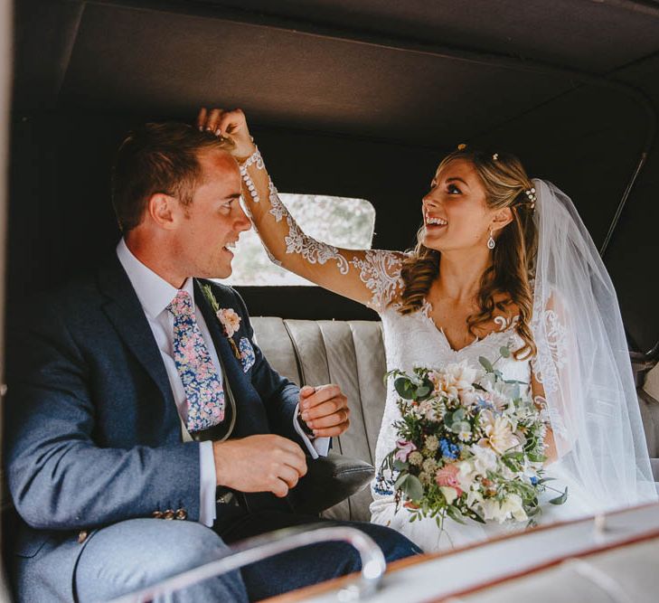 Bride in Lace Sincerity Bridal Wedding Dress Picking Confetti Out of Her Grooms Hair in the Back of The Vintage Wedding Car