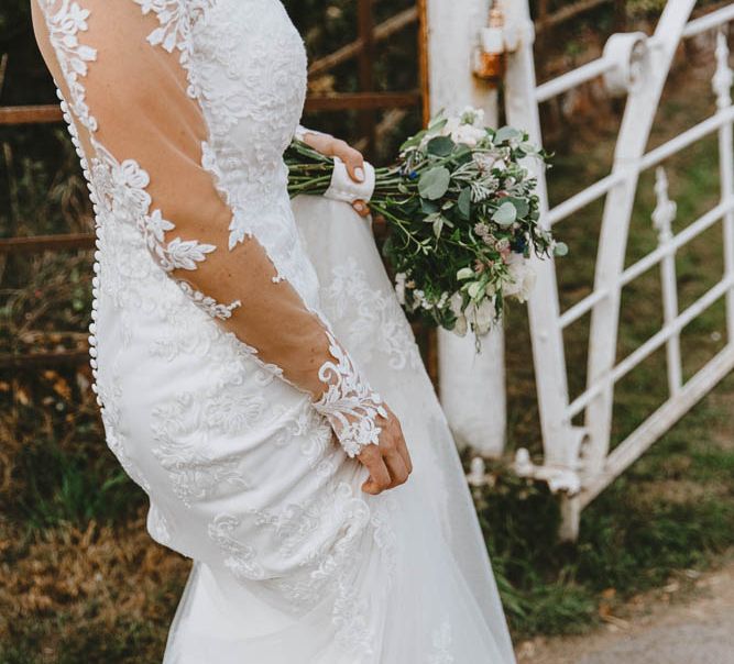 Bride in Lace Sincerity Bridal Wedding Dress with Long Sleeve Holding Up her Train