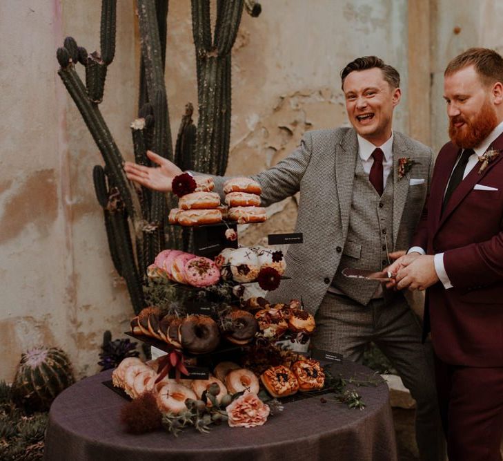 Groom and groom cutting the doughnut tower wedding cake