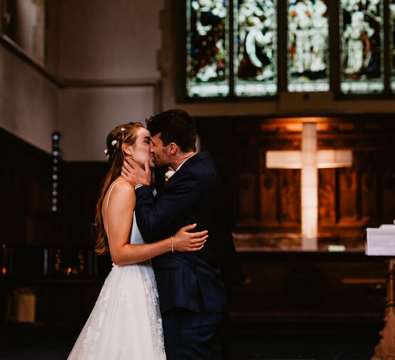 Bride and groom kiss during church wedding ceremony