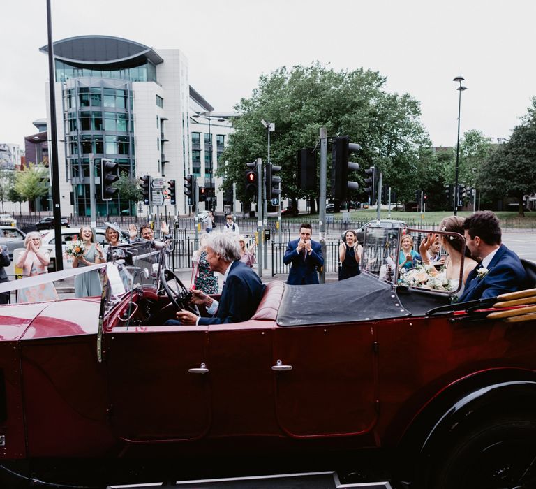 Bride and groom driving off in vintage wedding car