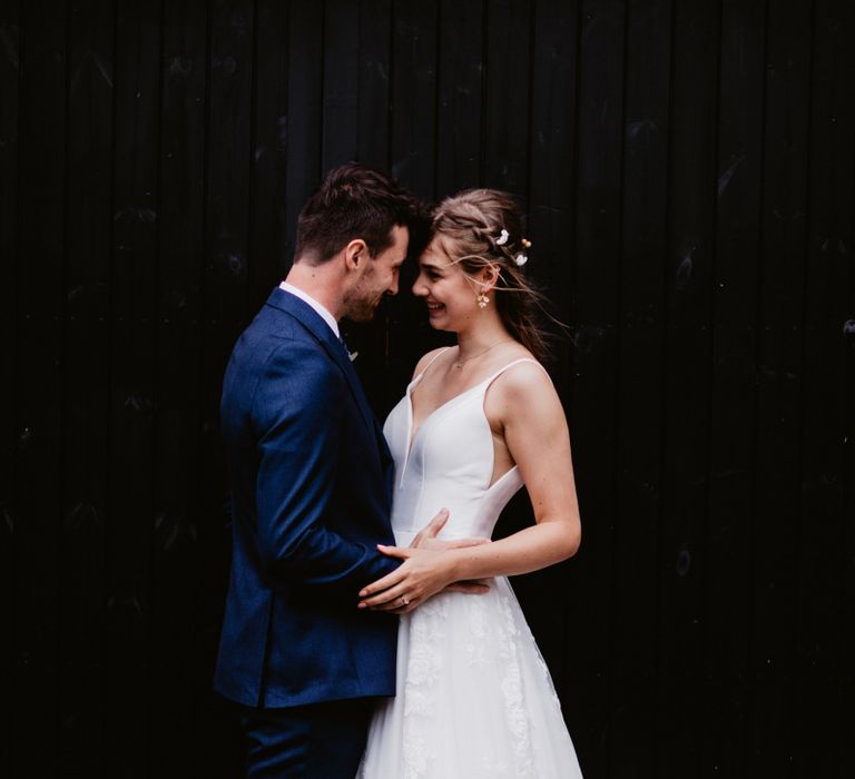 Bride in Essense of Australia wedding dress and groom in navy blue suit embracing