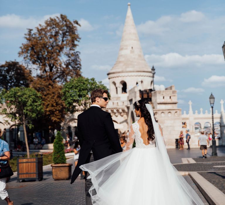 Bride in Pergola Rosa Clara Princess Wedding Dress and Groom in Traditional Morning Suit Walking the Streets on Budapest