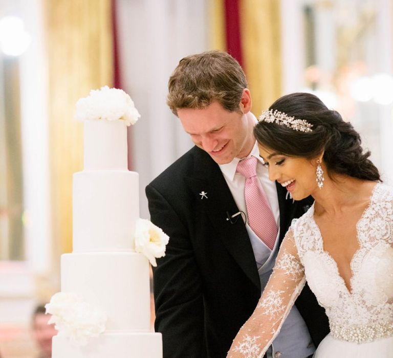 Bride in Pergola Rosa Clara Princess Wedding Dress and Groom in Traditional Morning Suit Cutting the Wedding Cake