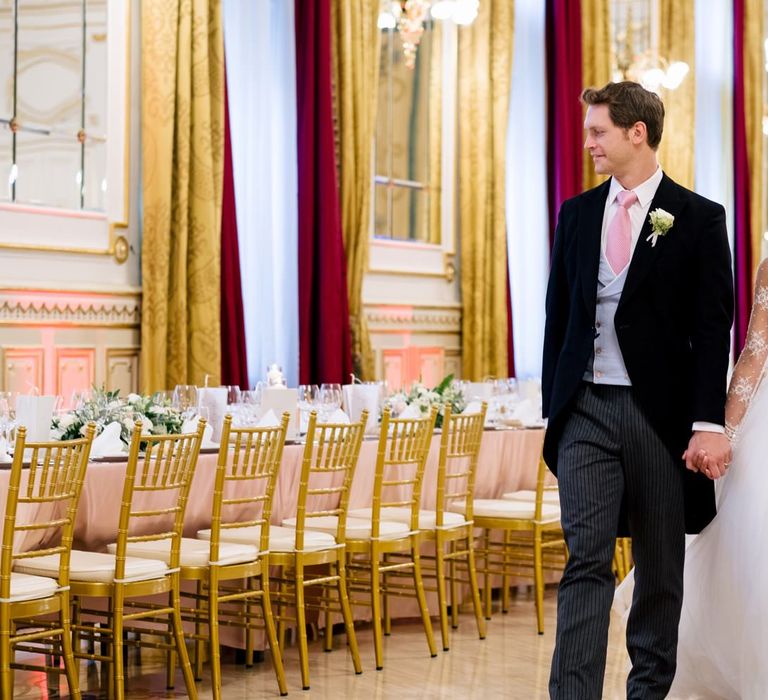 Bride in Pergola Rosa Clara Princess Wedding Dress and Groom in Traditional Morning Suit Walking Through The Wedding Reception Hall