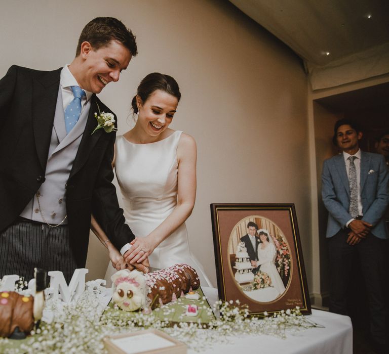 Bride and groom cutting their caterpillar wedding cake