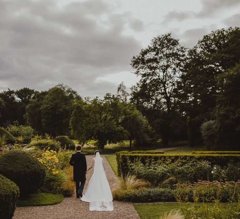 Bride and groom walking through the gardens at Shropshire wedding venue, Iscoyd Park