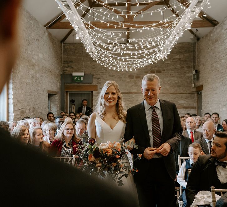 Bride walks down the aisle under fairy light canopy