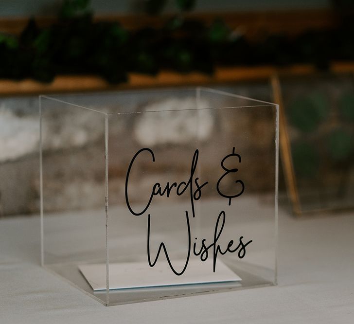 Glass box for cards next to unplugged wedding sign