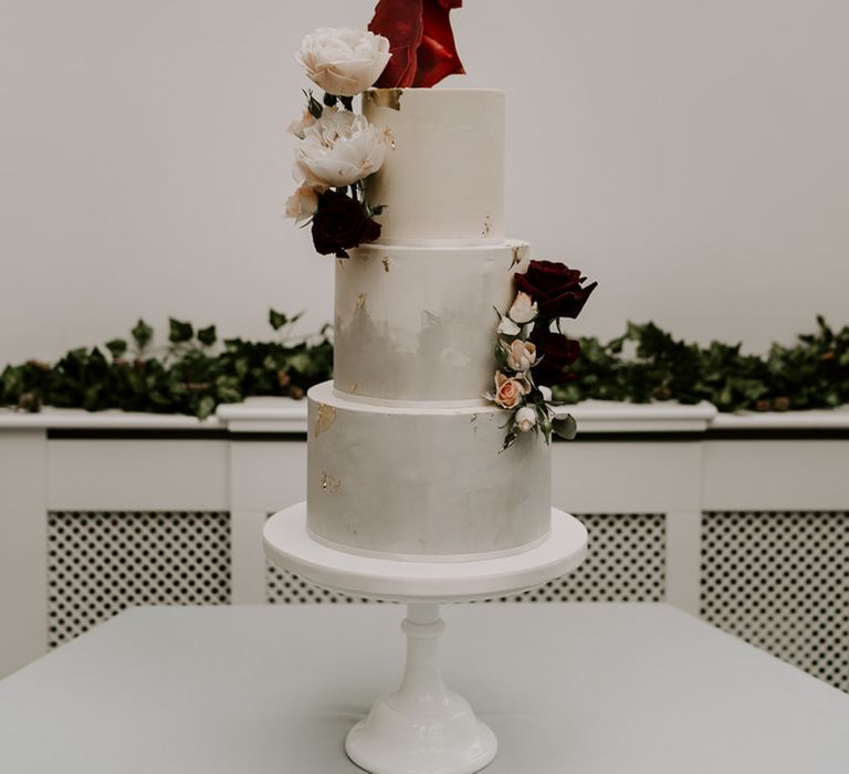 Marble wedding cake with flower decor at wedding with unplugged wedding sign