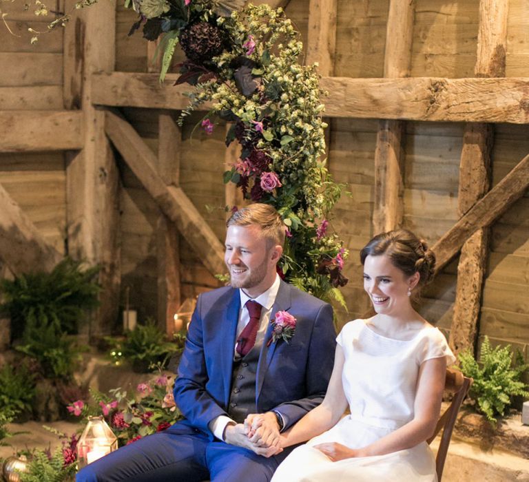 Bride in Jesus Peiro Wedding Dress and Groom in Blue  Hugo Boss Suit Sitting at their Moon Gate Altar