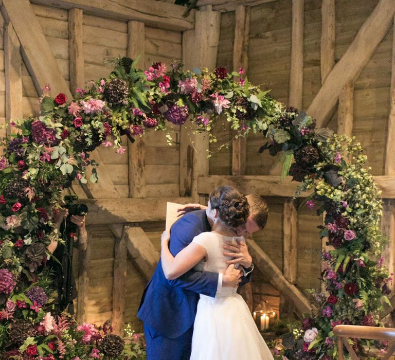 Bride in Jesus Peiro Wedding Dress and Groom in Blue  Hugo Boss Suit Hugging at The Moon Gate Altar