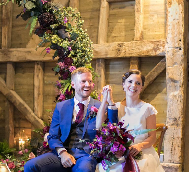 Bride in Jesus Peiro Wedding Dress and Groom in Blue  Hugo Boss Suit Holding Hands During Their Wedding Ceremony