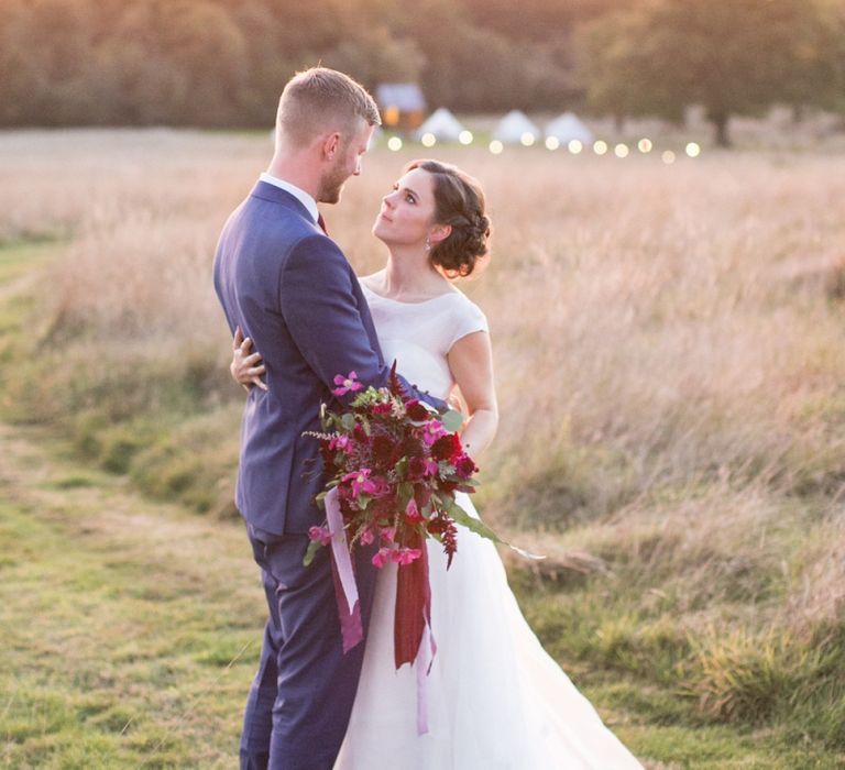 Bride in Jesus Peiro Wedding Dress and Groom in Blue  Hugo Boss Suit Embracing During Golden Hour