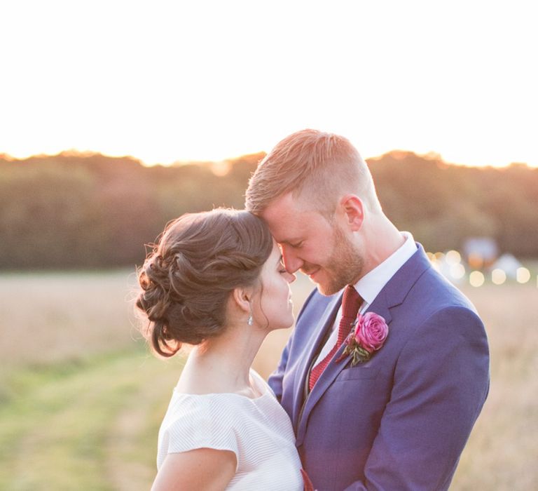 Bride in Jesus Peiro Wedding Dress and Groom in Blue  Hugo Boss Suit Embracing in the Countryside