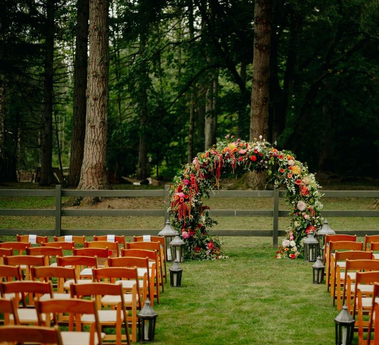 Outdoor wedding ceremony with brightly coloured flower arch