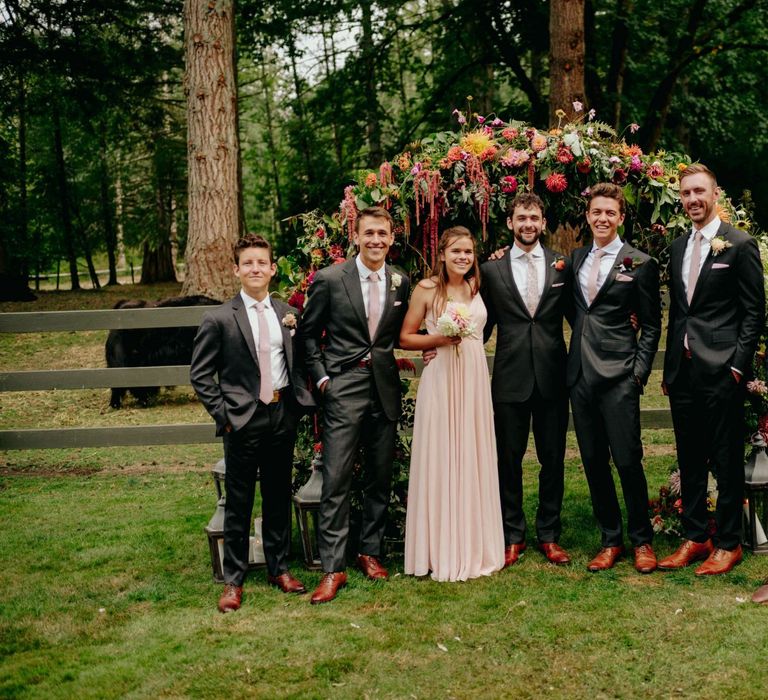 Groomsmen wedding party portrait in front of the flower arch