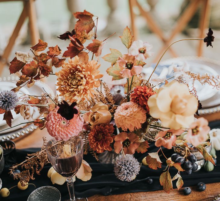 Autumn centrepiece with orange flowers and black candles