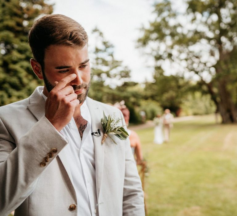 Groom in neutral suit gets emotional as bride walks down aisle